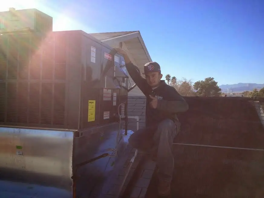 HVAC technician performing AC Tune-Up on a rooftop unit in Bixby